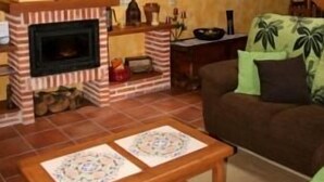 Un soggiorno con camino, una scala in legno e un divano con cuscini verdi.