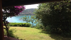 Vista de um lago rodeado de vegetação e céu claro.