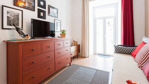 Ein modernes Schlafzimmer mit Fernseher, einem Holzschrank und einem großen Fenster mit roten Vorhängen.