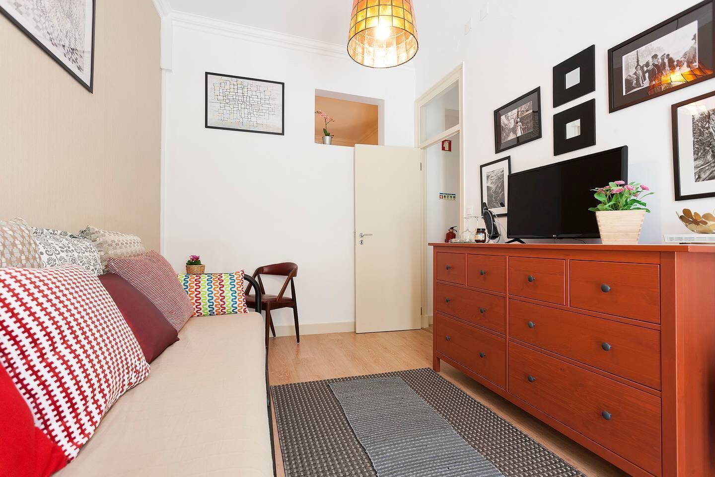 A bedroom with a bed, a wooden dresser, a chair, and a television.