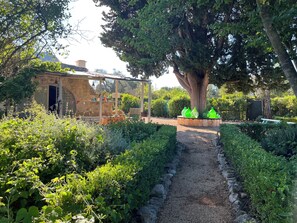A garden with a stone pathway leading to a covered seating area.