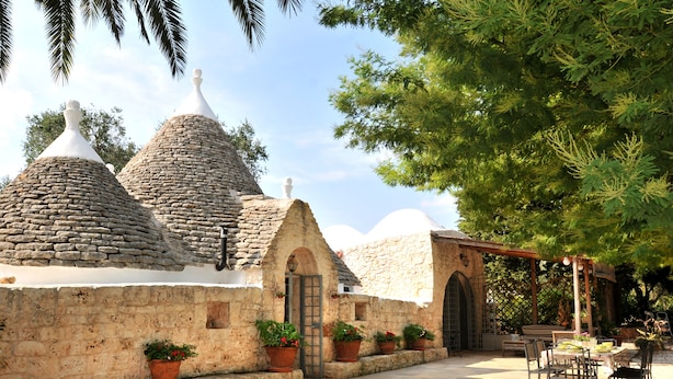 A courtyard with stone buildings, potted plants, and outdoor seating.