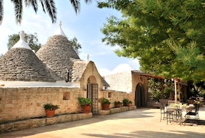 A courtyard with stone buildings, potted plants, and outdoor seating.