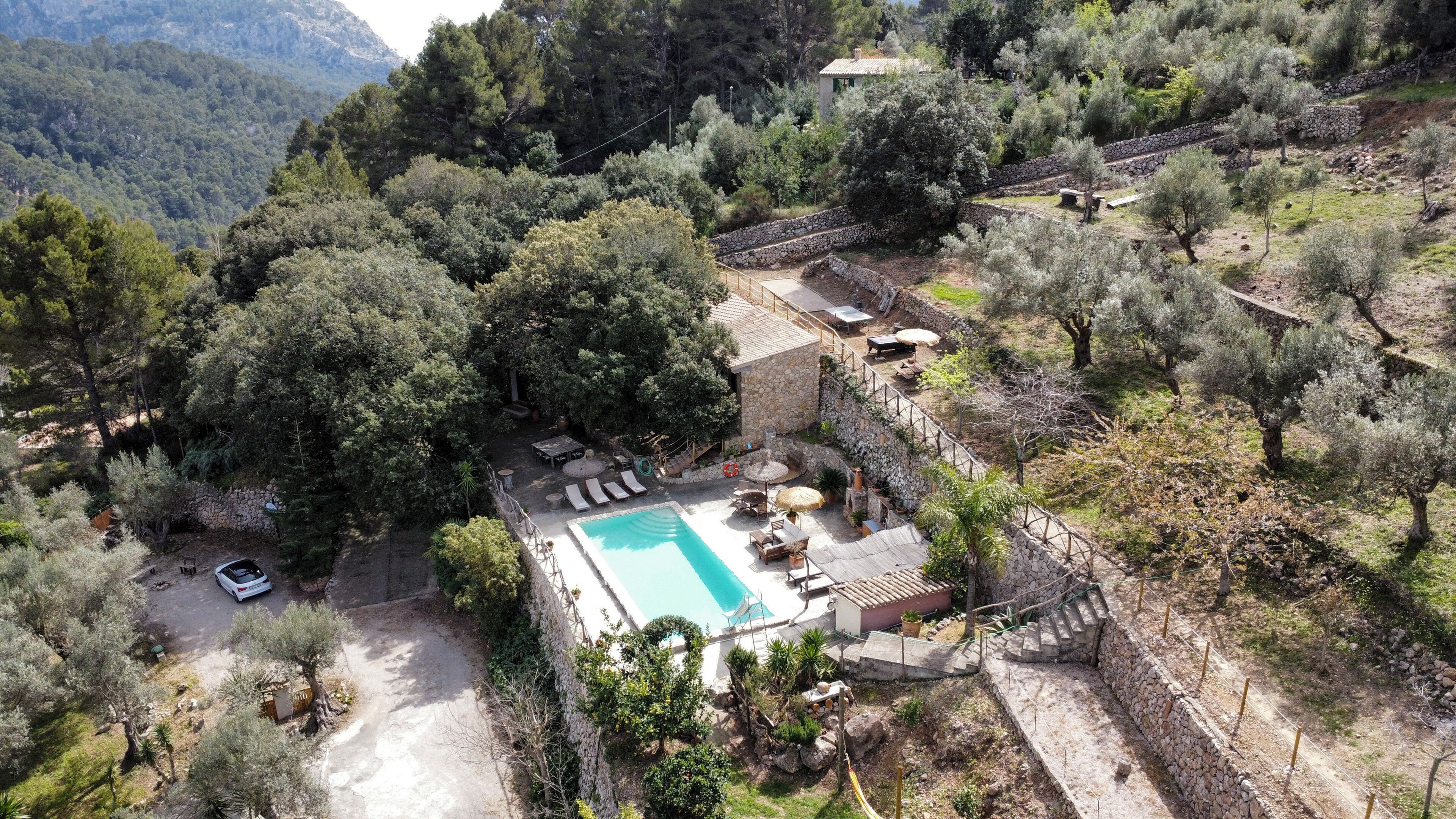 Area piscina con lettini, un muro in pietra e un edificio in pietra.