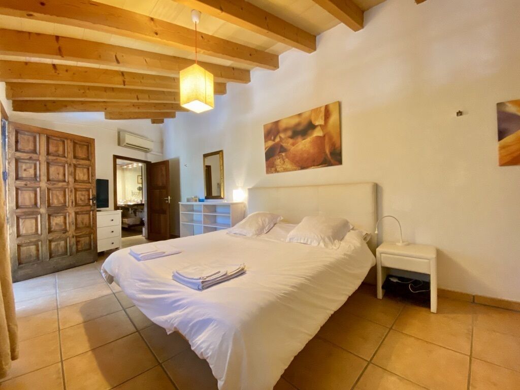 Une chambre à coucher avec un grand lit, une table de chevet, une armoire et une porte donnant sur une autre pièce.