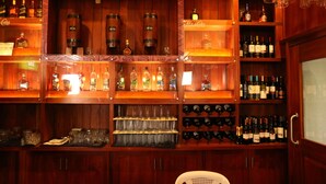 Un bar con estantes de madera llenos de diversas botellas y copas.