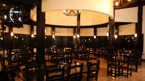 Un restaurante espacioso con numerosas mesas y sillas, un candelabro central y una decoración de estilo moderno.