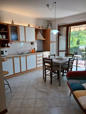 A kitchen with a dining area, a table with chairs, and a view of greenery outside. - Casa Grazia, quiet nest near the center. free parking all over the street. (Greve in Chianti)