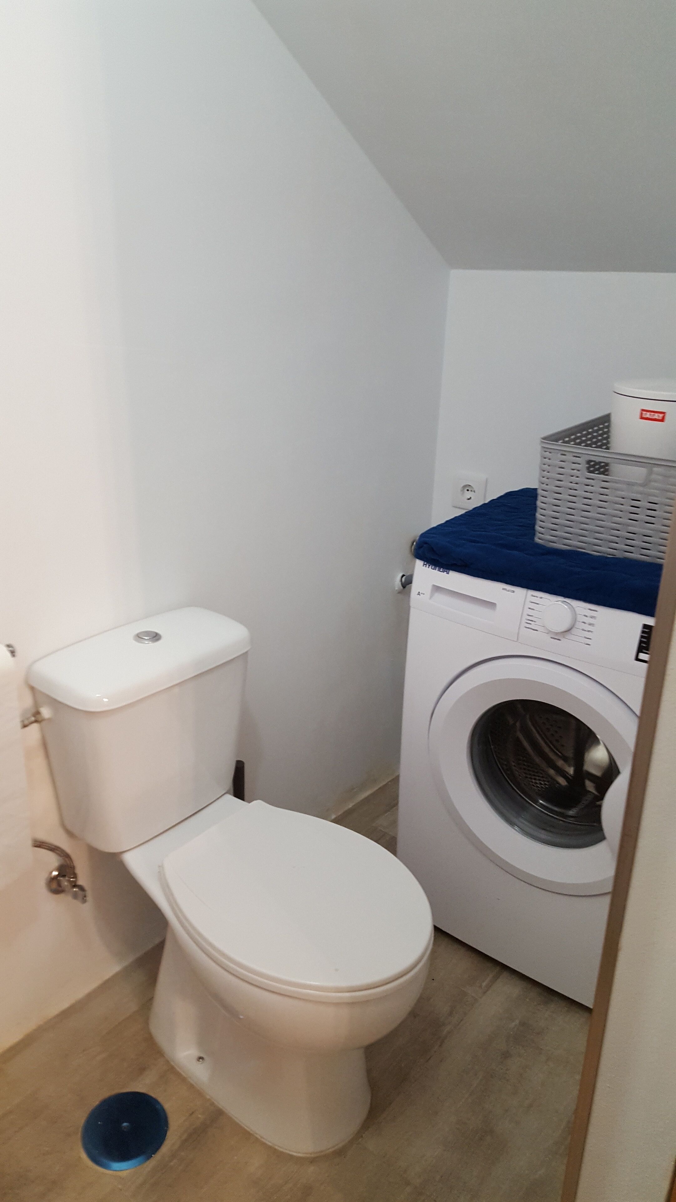 Een kleine, schone badkamer met een toilet en een voorlader wasmachine.