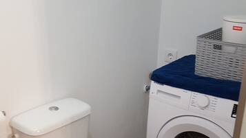 Een kleine, schone badkamer met een toilet en een voorlader wasmachine.