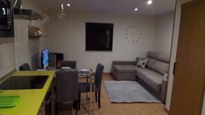 A compact living space with a dining table, chairs, a sofa, and a TV.