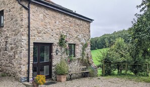 Un bâtiment en pierre avec une porte en bois sombre, un banc et une enseigne sur laquelle on peut lire : « The Apple Store ».