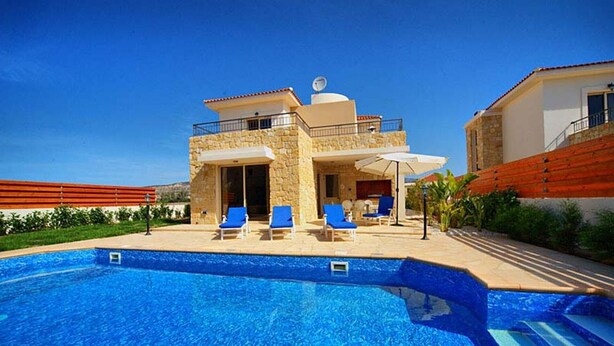 Eine moderne Villa mit Swimmingpool, Sitzgelegenheit im Freien und einer Steinfassade.