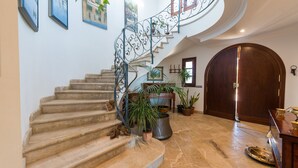 Un magnifique escalier en colimaçon orné d’une rampe en fer forgé, menant à une porte en bois.