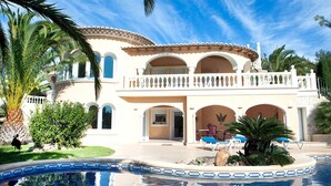 A large, two-story building with a pool, surrounded by palm trees and greenery. - Stunning private villa for 4 guests with WIFI, A/C, private pool, TV, patio and pets allowed (Benissa)