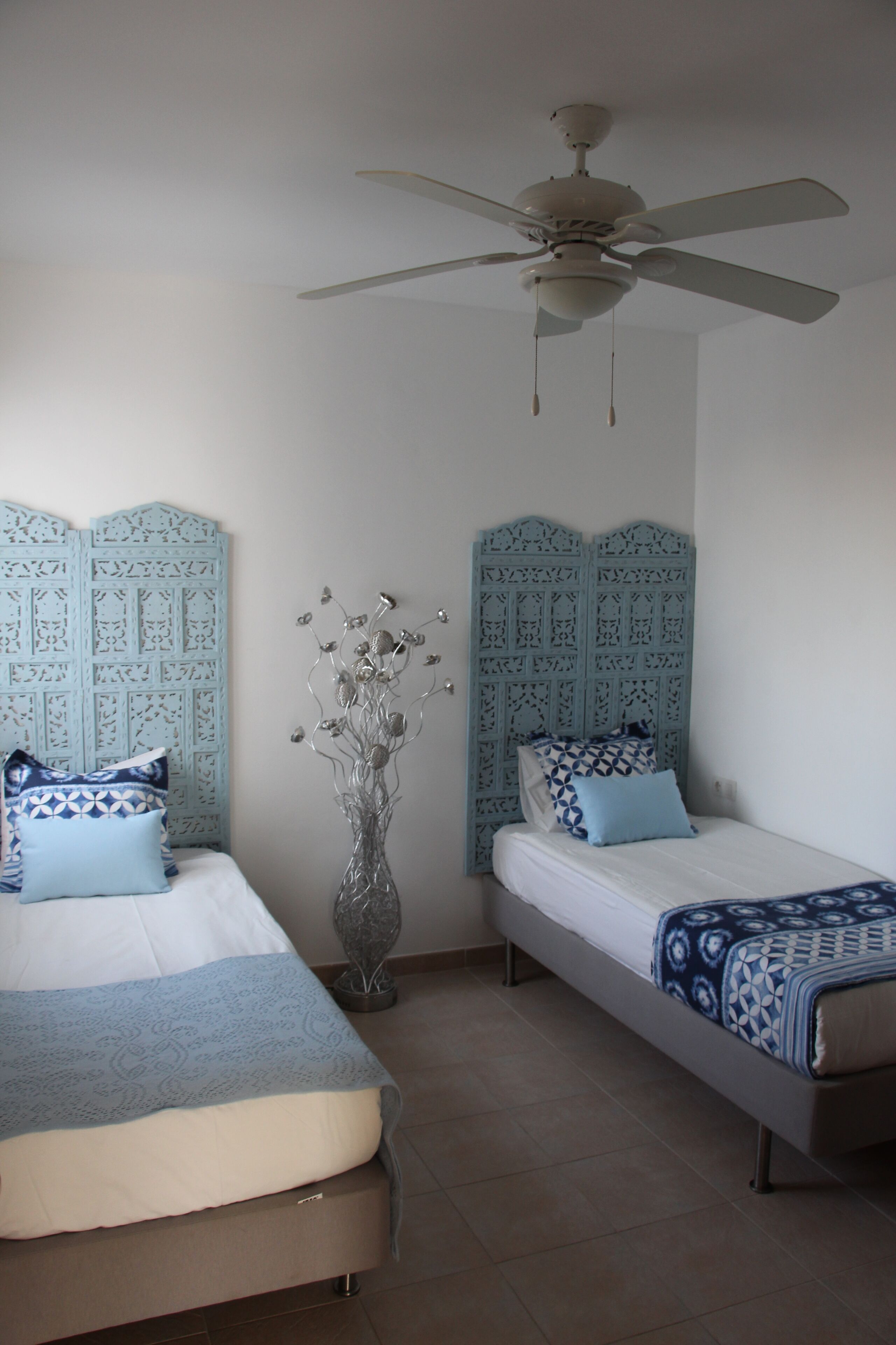 A bedroom with two beds, a ceiling fan, and decorative wall panels.