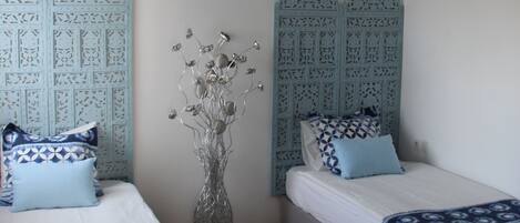 A bedroom with two beds, a ceiling fan, and decorative wall panels.
