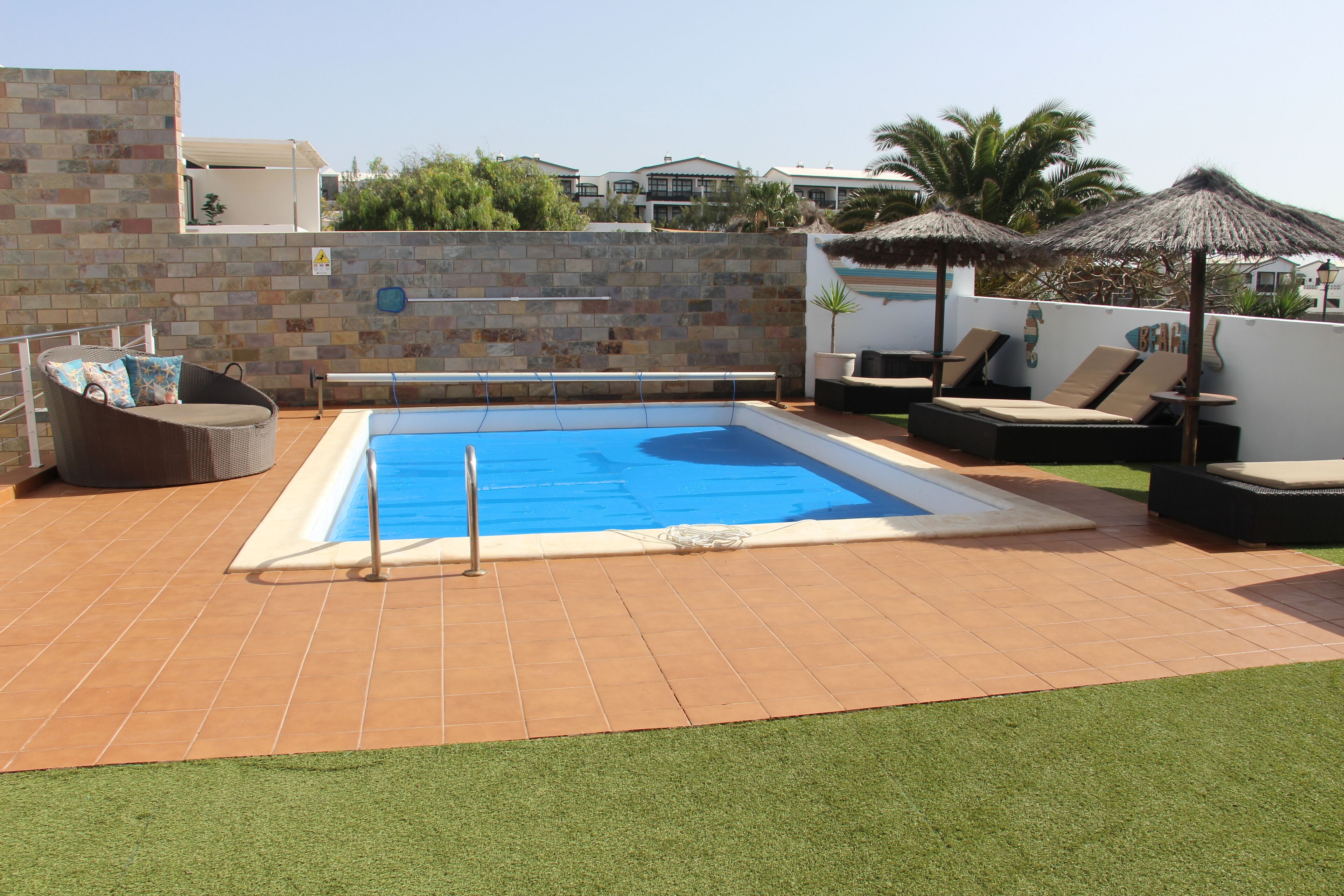 Une piscine avec un plongeoir, des chaises longues et un mur en briques.