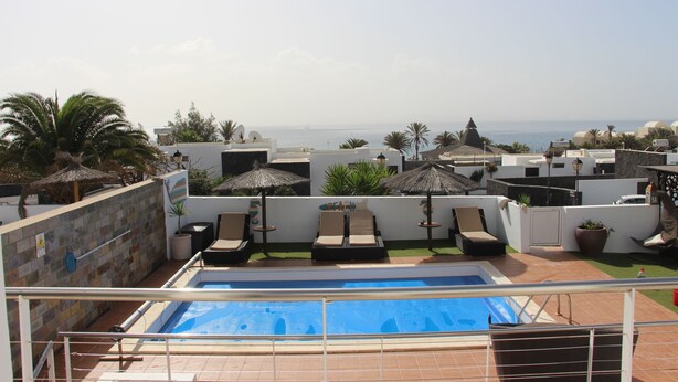 A rooftop pool area with lounge chairs and umbrellas, overlooking a coastal view. - Luxury Villa with Private Heated pool, FREE WiFi,  (Playa Blanca, Yaiza)