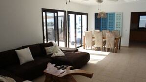 A living room with a sofa, a coffee table, and a dining area with chairs and a table. - Luxury Villa with Private Heated pool, FREE WiFi,  (Playa Blanca, Yaiza)