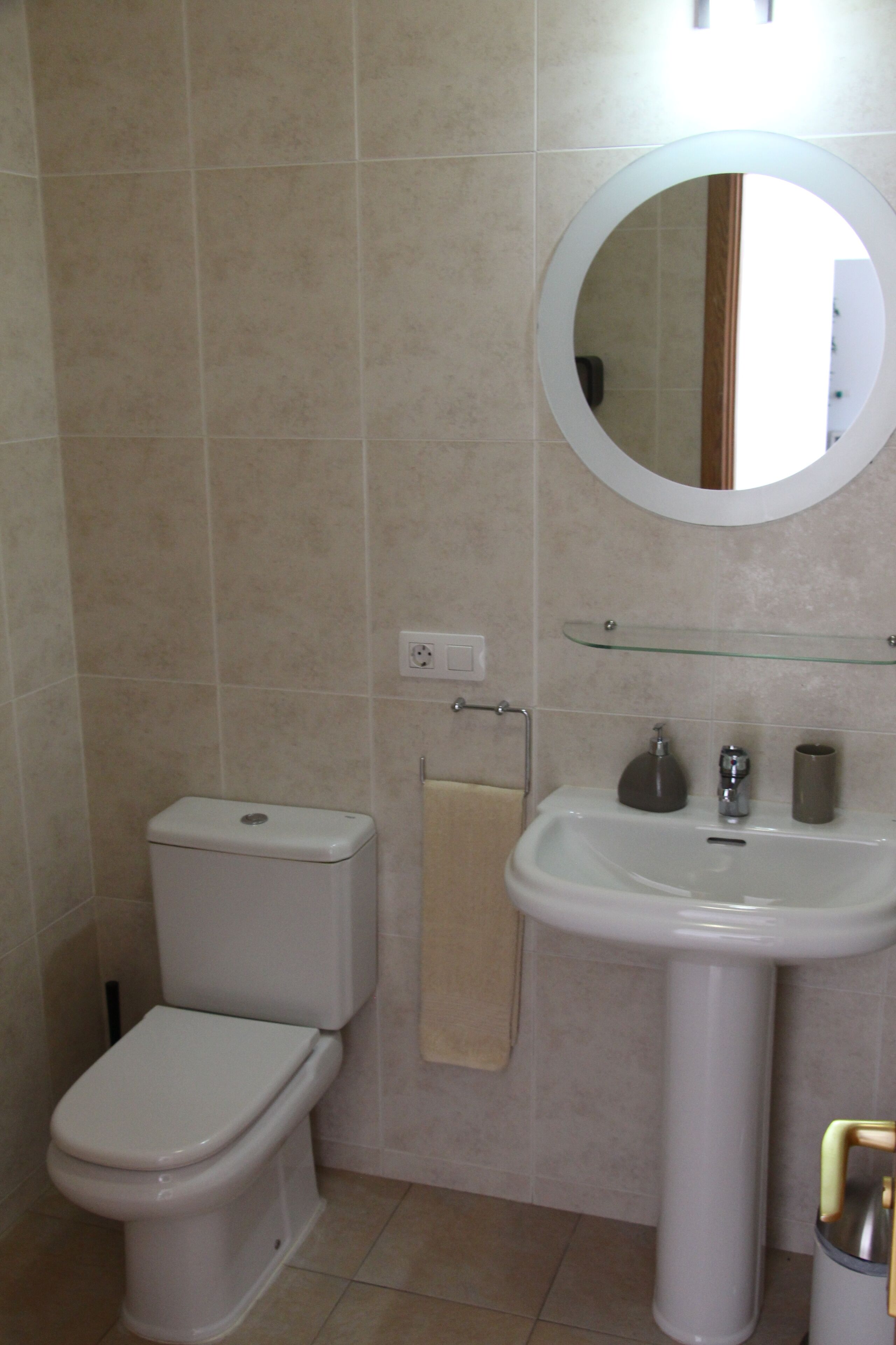 A bathroom with a toilet, sink, and mirror.