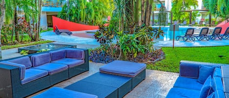 An outdoor lounge area with wicker furniture and a pool in the background.