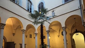 A courtyard with a palm tree in the center, surrounded by arches and columns.