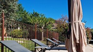 Outdoor lounge chairs and a covered umbrella in a sunny outdoor area with a clear blue sky. - Air-conditioned house 1 km Bédoin/Ventoux - Private/heated swimming pool - Wifi (Bédoin)