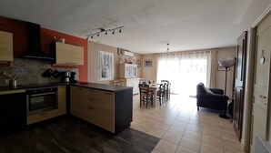 A modern kitchen with a central island, a dining area with chairs, a sofa, and a large window with curtains. - Air-conditioned house 1 km Bédoin/Ventoux - Private/heated swimming pool - Wifi (Bédoin)