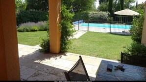 A covered patio area with a view of a swimming pool and a well-maintained lawn. - Air-conditioned house 1 km Bédoin/Ventoux - Private/heated swimming pool - Wifi (Bédoin)