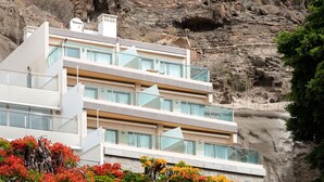 Un hôtel à plusieurs étages, doté de balcons, qui se dresse sur un fond de falaise rocheuse.