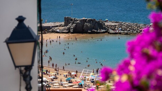 Une plage où l’on peut se baigner et bronzer, une zone rocheuse et un lampadaire.
