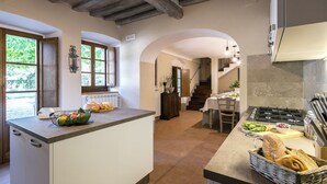 Eine Küche mit Kochinsel, ein Essbereich mit Tisch und Stühlen sowie eine Treppe, die in ein Obergeschoss führt.