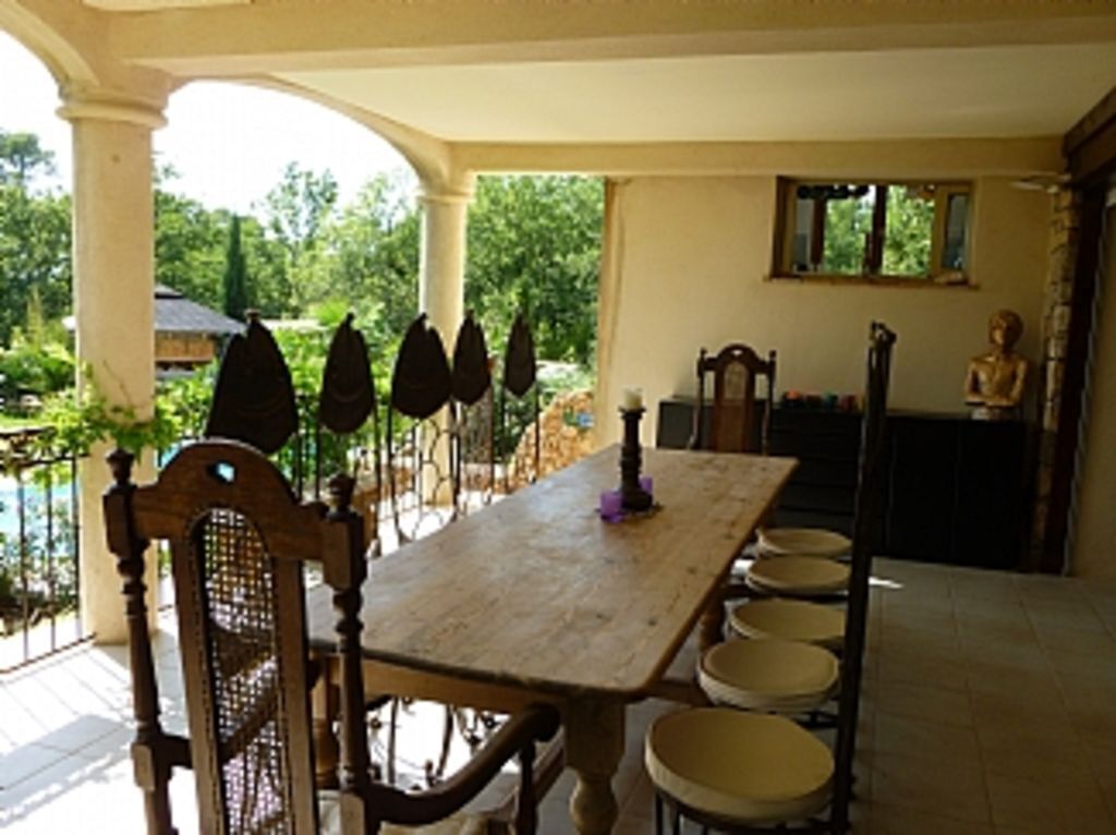 Un comedor con una mesa y sillas de madera, una estatua y un ventanal con vistas a zonas verdes.