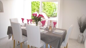A dining area with a table set for six, white chairs, and a vase of pink flowers. - House / Villa - CuersHouse with garden (Cuers)