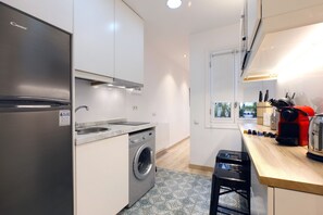 Eine moderne Küche mit einem Edelstahl-Kühlschrank, einer integrierten Waschmaschine und einer Holzausziehtheke mit verschiedenen Geräten.