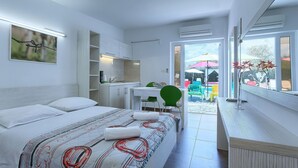 A modern bedroom with a bed, a desk, and a view of an outdoor patio area. - Lovely apartment for 2 people with WIFI, pool, A/C, TV and terrace (Umag)