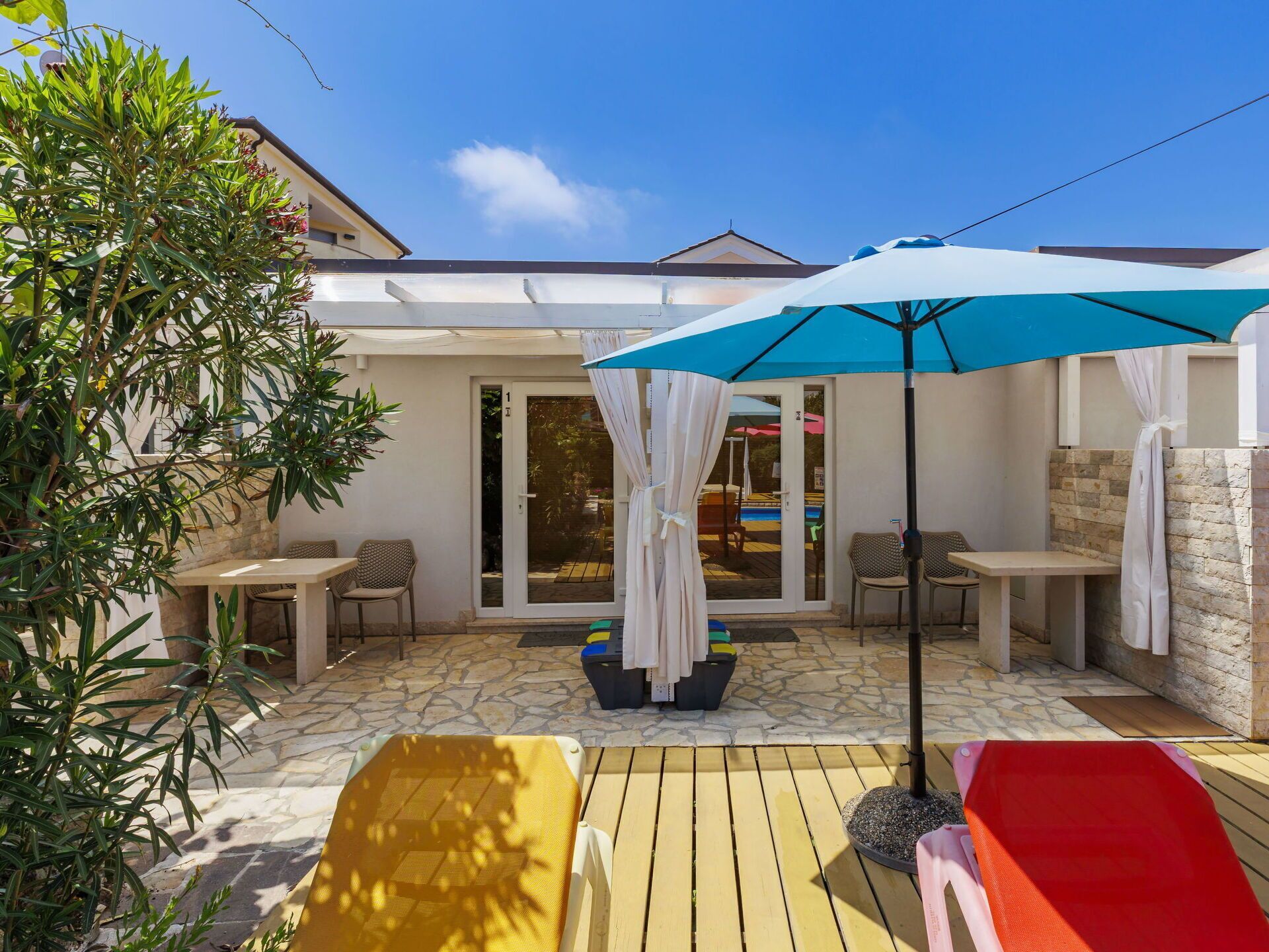 Eine Terrasse mit Gartenmöbeln, einem Pool und einem überdachten Bereich mit Sonnenschirmen.