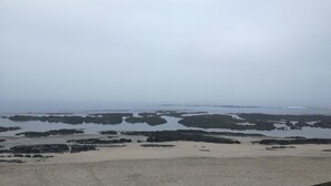 A coastal landscape with rocky outcrops and sandy beach areas.