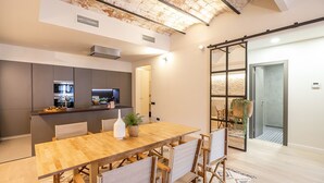 A modern kitchen with built-in appliances, a dining area with a wooden table and chairs, and a large sliding glass door leading to an outdoor area.