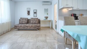 A modern living room with a sofa, a dining table, and a kitchenette. - Beautiful apartment for 6 guests with WIFI, pool, A/C, TV and terrace (Umag)