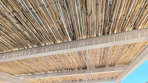 Un balcon doté d’un plafond en bambou, de murs blancs et d’une table recouverte d’une nappe à motifs d’étoiles de mer.