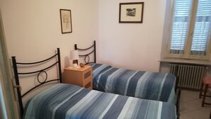 A bedroom with two beds, a bedside table with a lamp, and a radiator. - Holiday Monferrato - LE GINESTRE - WI-FI AND PARKING FREE (Tonco)