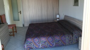 A bedroom with a bed, a chair, a nightstand, a lamp, and a door. - Holiday Monferrato - LE GINESTRE - WI-FI AND PARKING FREE (Tonco)