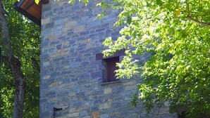 Ein Steinhaus mit einer großen, bogenförmigen Holztür, Blumentöpfen und einer Bank vor der Fassade.