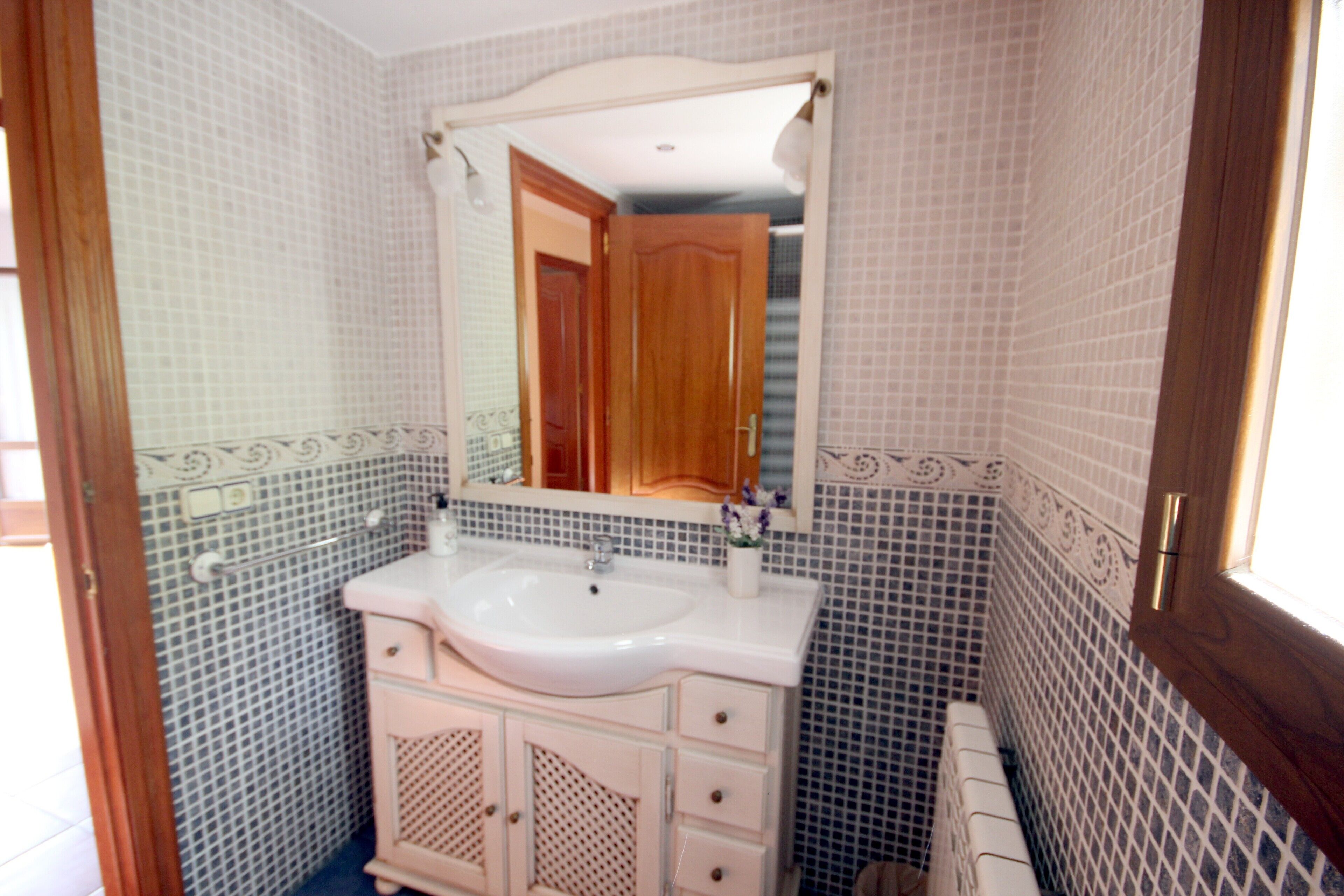 A bathroom with a white sink, a mirror, and a wooden door.