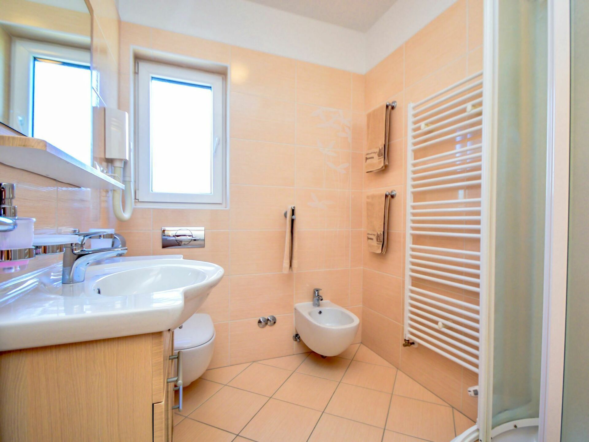 Une salle de bain moderne équipée d’un lavabo, de toilettes, d’un bidet et d’un porte-serviettes.