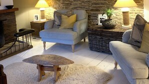 A cozy living room with a stone wall, two sofas, a coffee table, and two lamps. - Waterside cottage in a  magical setting on the Salcombe Estuary (sleeps 6) (Kingsbridge)