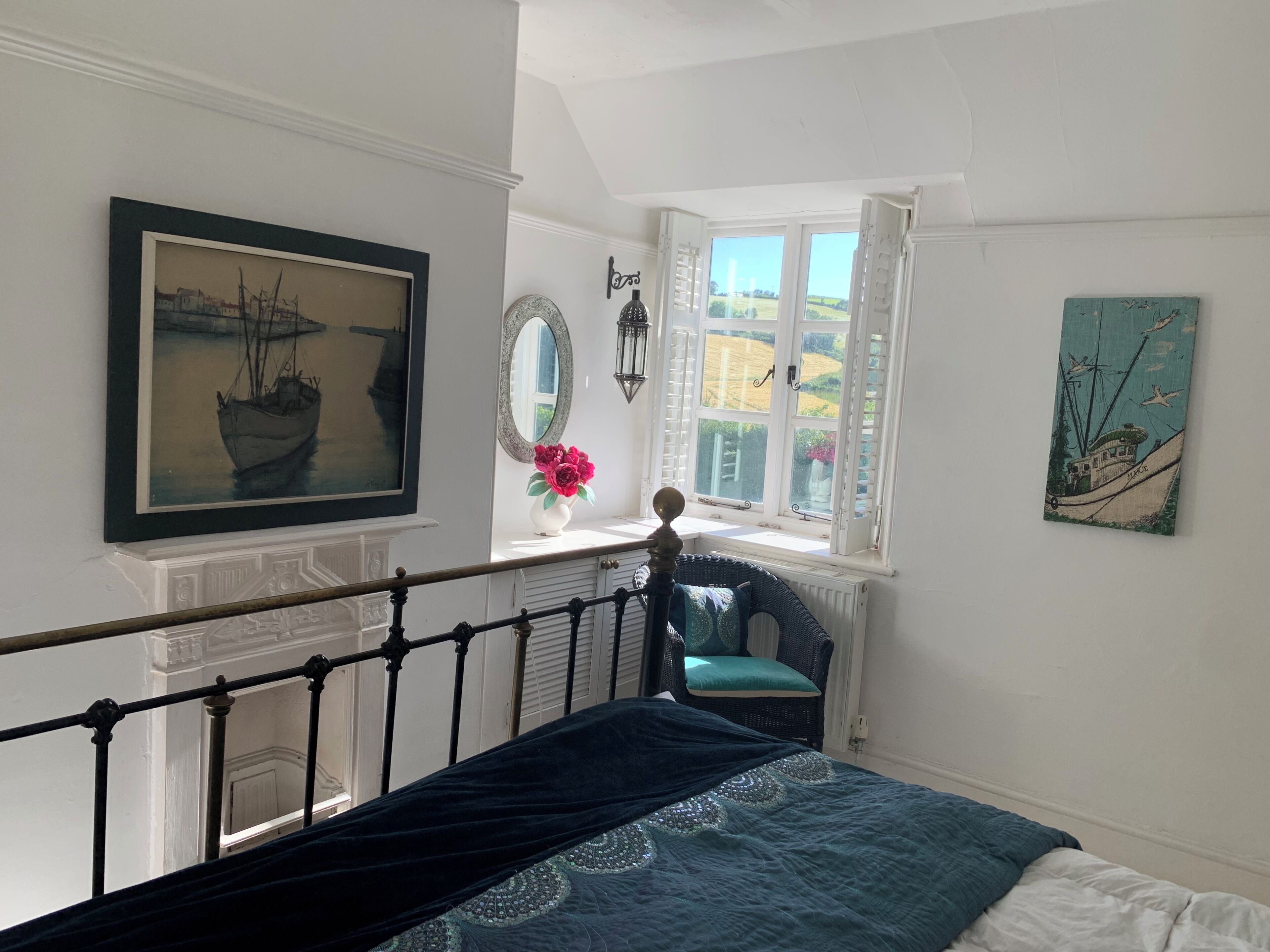 Een slaapkamer met een bed, een raam met uitzicht, een stoel en wanddecoratie.