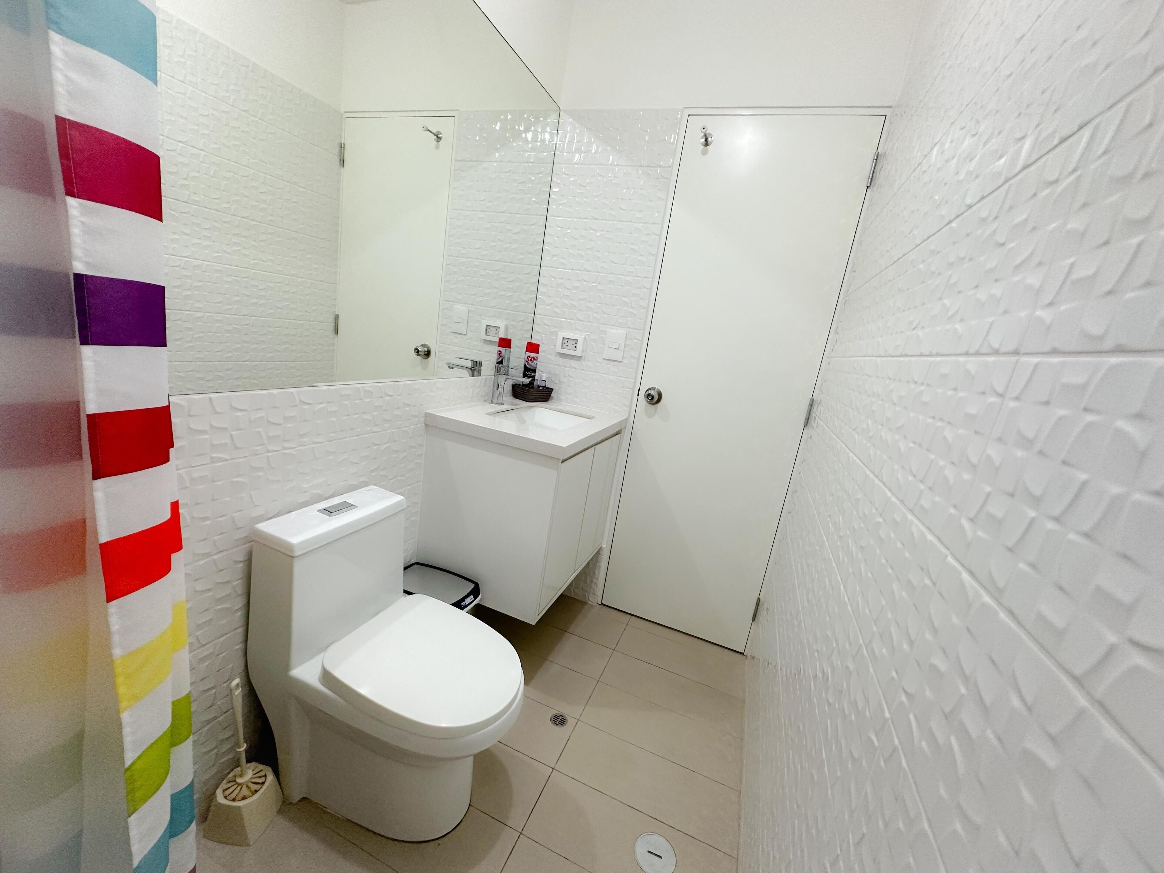 A small, modern bathroom with a white toilet, a sink, and a mirror.